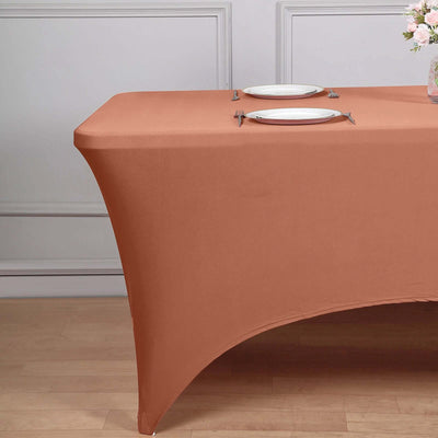 Brown fitted tablecloth on a dining table with plates and flowers.