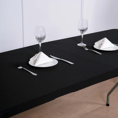 Elegant dining setup with black tablecloth, plates, and glassware.