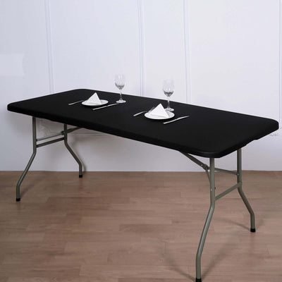 Black folding table set for dining with plates and glasses.