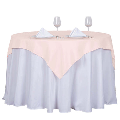 Round table with pink and light blue tablecloth, set with plates and glasses.