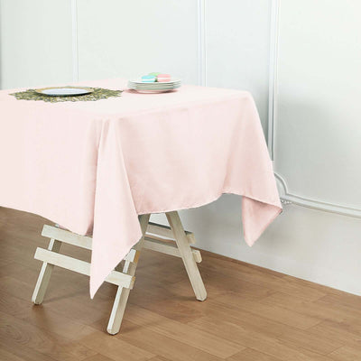 Pink tablecloth draped on a wooden table with decorative plate and macaroons.