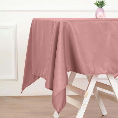 Pink tablecloth draped over a wooden table with a vase and flowers.