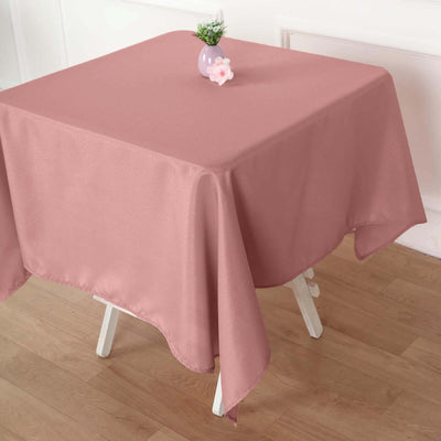 Pink tablecloth draped over a table with a small vase on top.