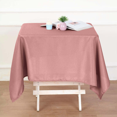 Pink tablecloth draped over a wooden table with decor items.