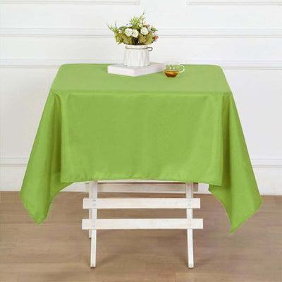 Green tablecloth draped over a wooden table with a floral centerpiece and tea.