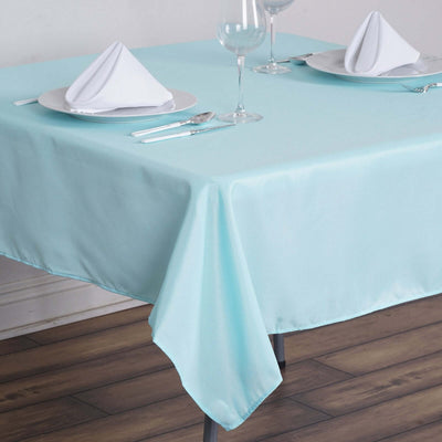 Light blue tablecloth on a dining table set with plates and glasses.