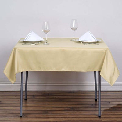 Elegant beige tablecloth set with glasses and folded napkins on a dining table.