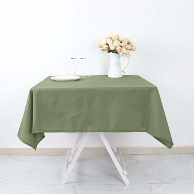 Green tablecloth draped over a table with flowers and glassware.