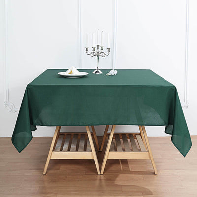 Green tablecloth draped over a wooden table with a candle holder and plate.