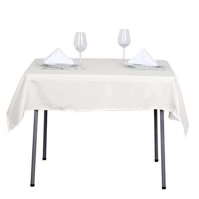 Elegant dining table set with white tablecloth, plates, and glasses.