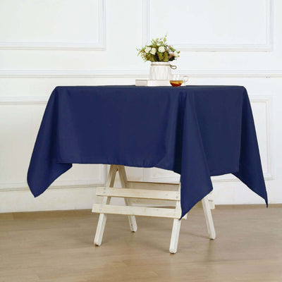 Navy blue tablecloth draped on a wooden table with a vase and tea cup.