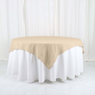 Beige tablecloth draped over a round table with a white skirt.