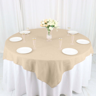 Beige round tablecloth on a dining table with floral centerpiece and plates.