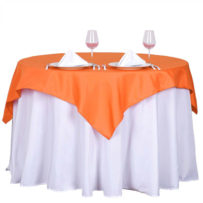 Round table with orange tablecloth, white linens, and dining setup.