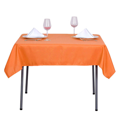 Orange tablecloth set with wine glasses and napkins on a dining table