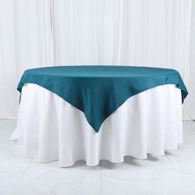 Teal tablecloth draped over a round table with a white skirt.