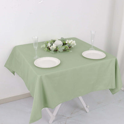 Elegant green tablecloth set for a dining table with plates and decorative centerpiece.