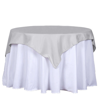Gray tablecloth draped over a round table with a white skirt