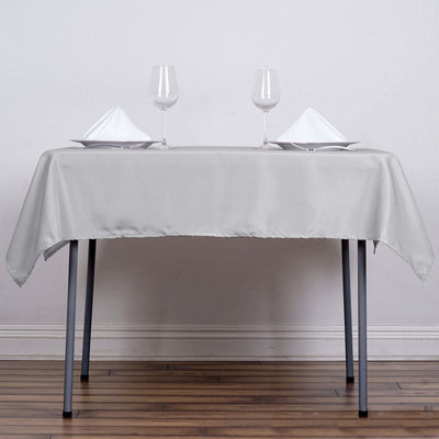 Elegant silver tablecloth with wine glasses and napkins on a dining table.