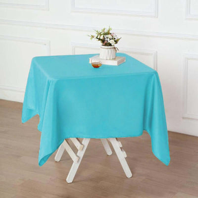 Turquoise tablecloth draped over a wooden table with decor items.