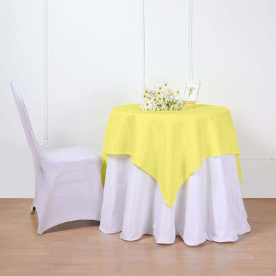 Yellow tablecloth draped over a round table with a floral centerpiece.