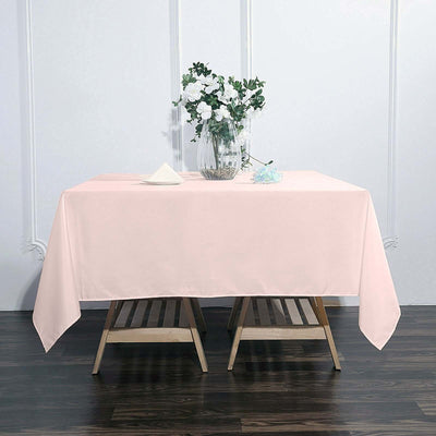 Pink tablecloth on a wooden table with a floral centerpiece.