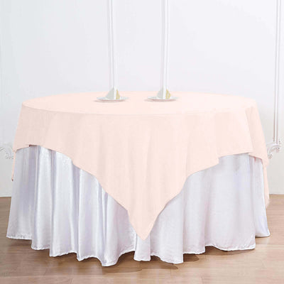 Pink tablecloth draped elegantly over a round table with candles.