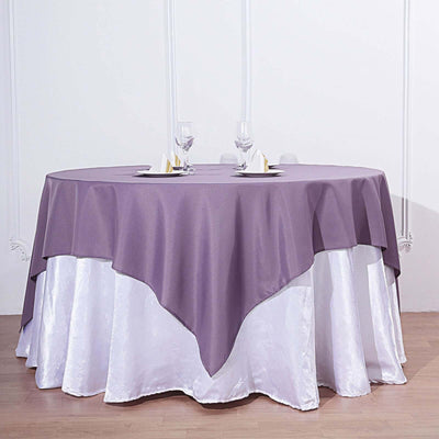 Round table with purple tablecloth and elegant glassware setup.