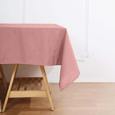 Pink tablecloth draped over a wooden table in a bright room.