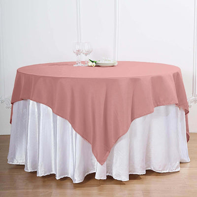 Round table with a pink tablecloth and white skirt, set with plates and glasses.
