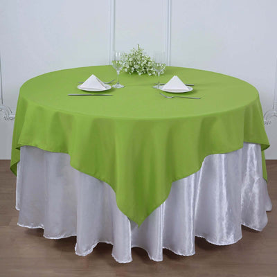 Round green tablecloth draped over a silver table, set for dining.