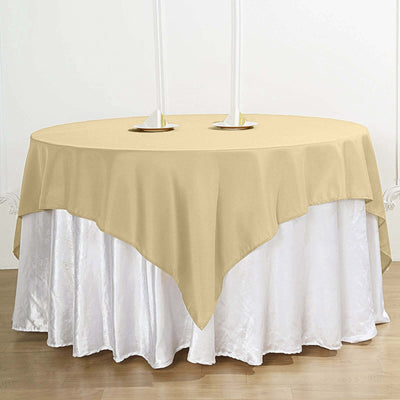 Round beige tablecloth on a white table with candle holders.