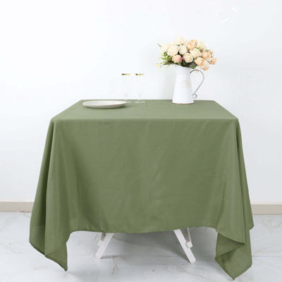 Green tablecloth on a table with a vase of flowers and glassware.