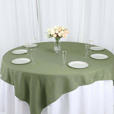 Olive green round tablecloth with plates and glasses set for dining.