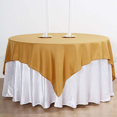 Gold tablecloth draped over a white table with candle holders.