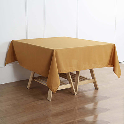 Square mustard tablecloth draped over a wooden table.