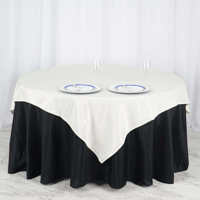 Round table with white tablecloth and black skirt, set for dining with two plates.
