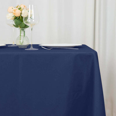 Navy tablecloth with elegant dinnerware and floral centerpiece on a table.