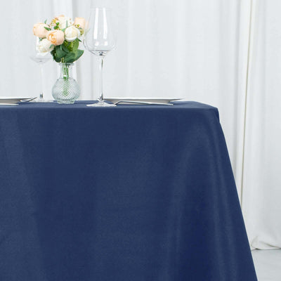 Navy tablecloth draped elegantly on a dining table with glassware and flowers.