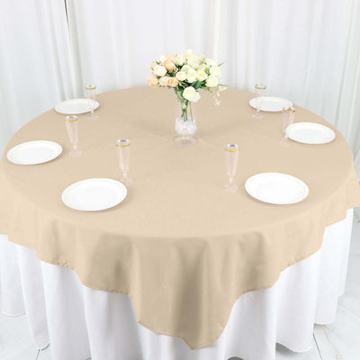 Round beige tablecloth with plates and glasses set for an elegant dining experience.