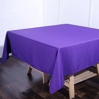 Purple tablecloth draped over a wooden table in a studio setting.