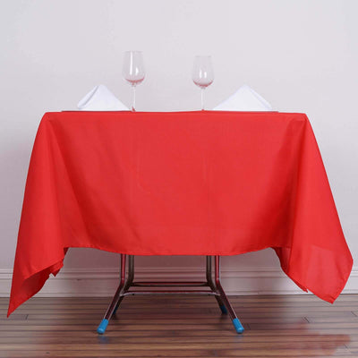 Red tablecloth draped over a table with glasses and napkins.
