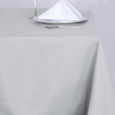 Gray tablecloth draped over a table with a plate and napkin on top.