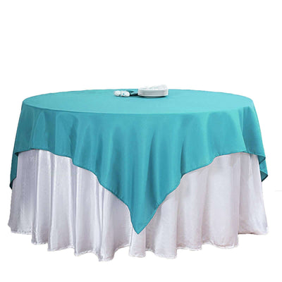 Round table with a turquoise tablecloth and white skirt.