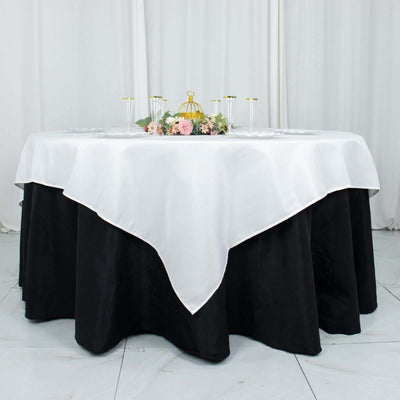 Elegant round table with black and white tablecloth, adorned with floral centerpiece.