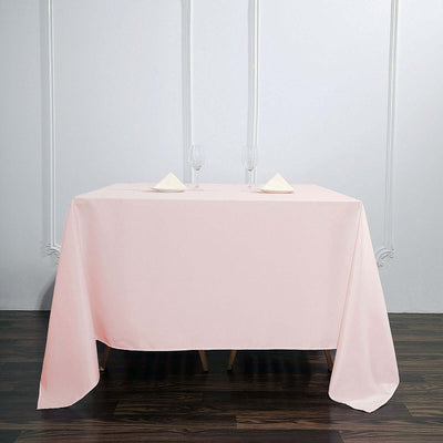 Pink tablecloth draped over a table, set with glassware and napkins.