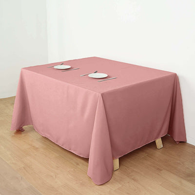 Pink tablecloth draped over a table set for two with plates and utensils.