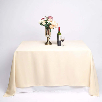 Beige tablecloth with a vase of flowers, wine bottle, and glass on a table.