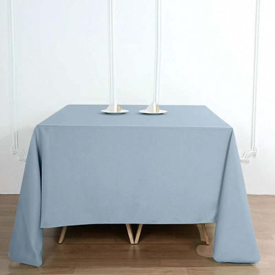Light blue tablecloth draped over a wooden table with candle holders.