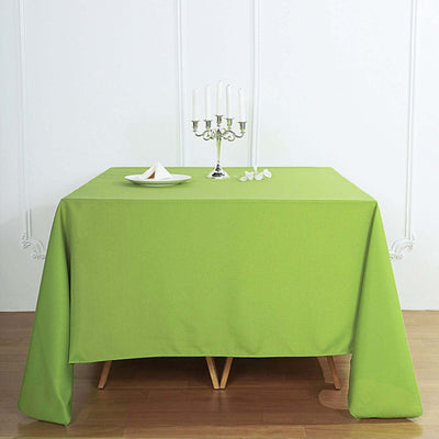 Green tablecloth on a wooden table with a candle holder and napkin.